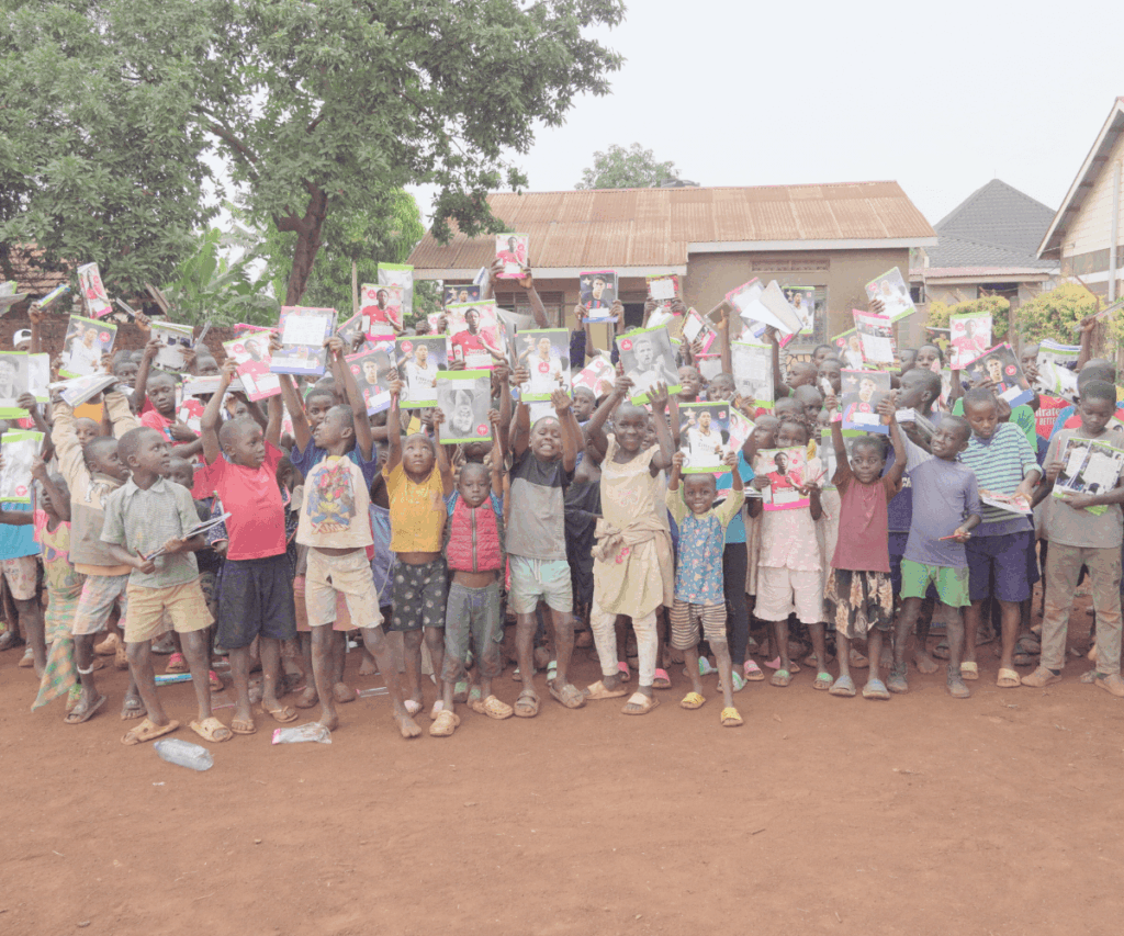 Large group of kids in Uganda holding up workbooks donated by Signature Foundation