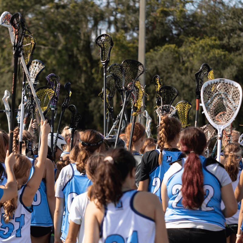 Group of girls lacrosse players hold up their sticks during a huddle
